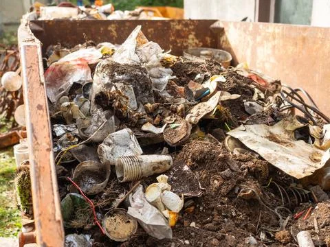 Rusty Dumpster Filled with Soil and Mixed Plastic Waste Stock Photos