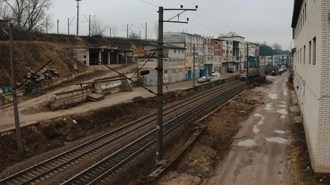 A rusty electric train moves along urban garages, like a slums. Stock Footage 130026003