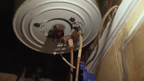 Rusty Electric Water Heater Bottom View with Exposed Wiring and Corroded Pipes Stock Footage 336643894