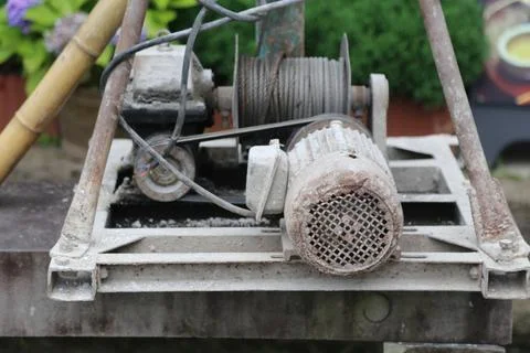 Rusty electric winch motor with cable spool on an outdoor metal platform Stock Photos