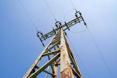 Rusty electricity pylon with high voltage power lines in the blue sky Stock Photos