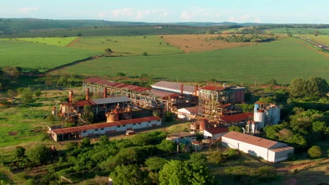 Rusty ethanol plant surrounded by green fields under a sunny sky, aerial Stock Footage 296320904