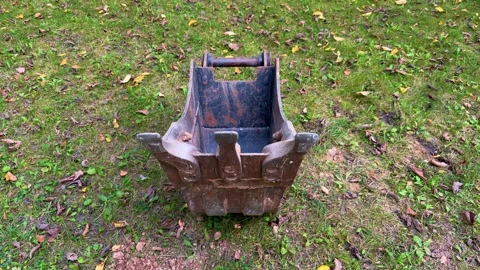 Rusty excavator bucket attachment standing on grass outdoors Video stock 346516033