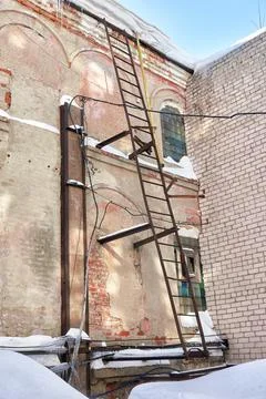 A rusty fire escape on the wall of an old industrial building. Winter view. Stock Photos