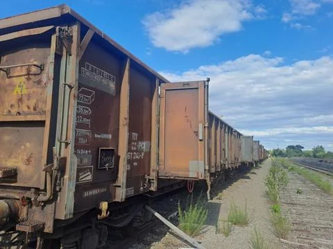 Rusty freight train wagons on railway tracks under blue sky. Stock Photos