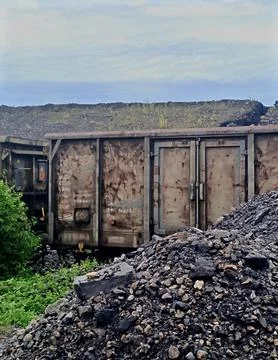 Rusty freight wagon surrounded by coal and industrial spoil. Stock Photos