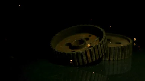 Rusty gears on dark surface with falling golden sparks Stock Footage 327514503