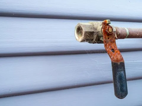 Rusty handle at the end of an open pipe covered in cobwebs outside Stock Photos
