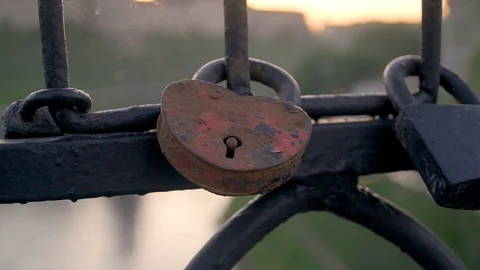 Rusty heart-shaped lock fastened on a fence of metal bars Stock Footage 127583847