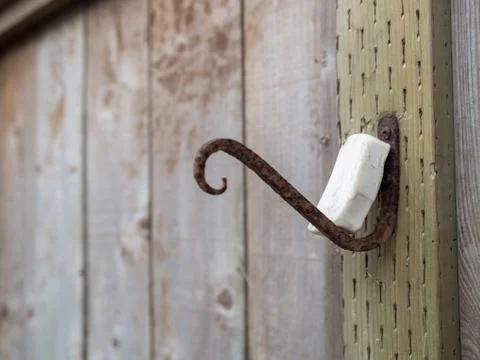 Rusty hook with bar of soap resting in an outdoor fence area Stock Photos
