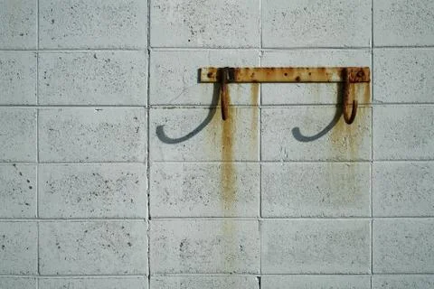 Rusty hooks on a breeze block wall. Stock Photos