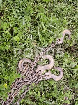 Rusty hooks with chains lying on the grass Stock Photos