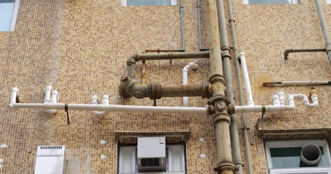Rusty iron and plastic white pipes of exposed drainage at building facade Stock Footage 309361892