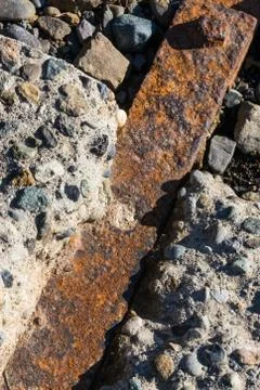 Rusty iron bar impregnated between rocky concrete blocks Stock Photos