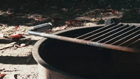 Rusty iron campfire pit sits unused with fine cobwebs Stock Footage 336673309