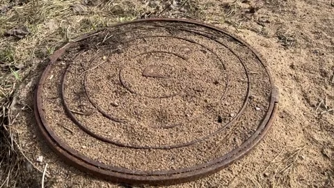 A rusty iron hatch covered grains of sand and the ground with a pattern above an Vidéo 316806406