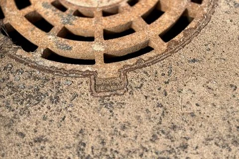A rusty iron hatch with a pattern above an observation well is located on auto Stock Photos