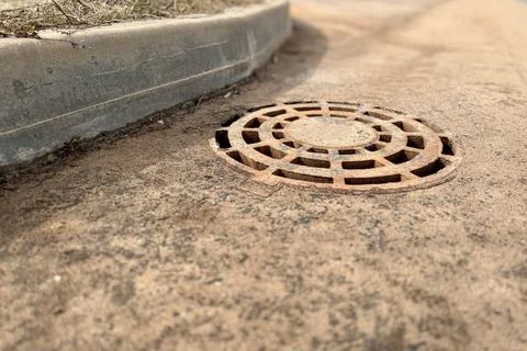 A rusty iron hatch with a pattern above an observation well is located on auto Stock Photos