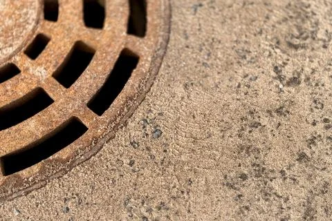A rusty iron hatch with a pattern above an observation well is located on auto Stock Photos