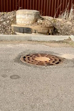 A rusty iron hatch with a pattern above an observation well is located on auto Stock Photos