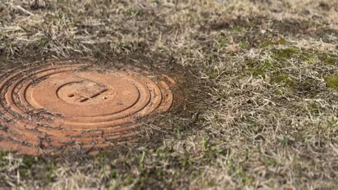 A rusty iron hatch with a pattern covered dirt above an observation well is Stock Footage 274598766