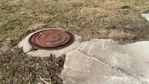 A rusty iron hatch with a pattern covered dirt above an observation well is Stock Footage 299617214