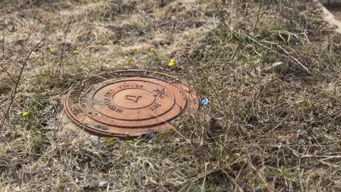 A rusty iron hatch with a pattern covered dirt above an observation well is Stock Footage 316806408
