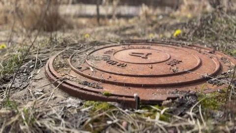 A rusty iron hatch with a pattern covered dirt above an observation well is Stock Footage 316806474