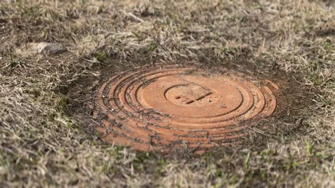 A rusty iron hatch with a pattern covered dirt above an observation well is Stock-Footage 316806630