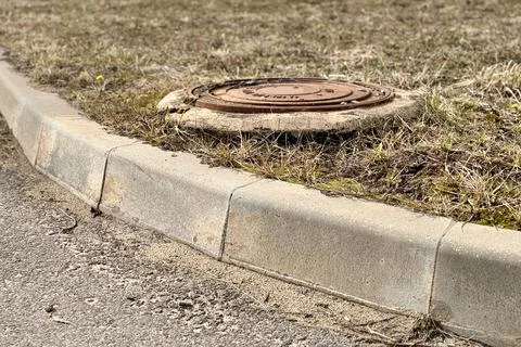 A rusty iron hatch with a pattern covered dirt above an observation well is Stock Photos