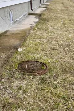 A rusty iron hatch with a pattern covered moss above an observation well is Stock Photos