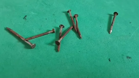 Rusty iron nails scattered on a vibrant green textured video background Stock Footage 339249017