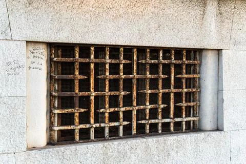 Rusty iron security grate covering basement window embedded in rough granite Stock Photos