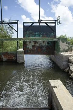 Rusty iron sluice gate controls water flow in ancient irrigation network of.. Stock Photos