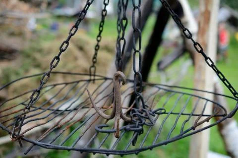 Rusty iron triple hook on grate hanging on chains. Shallow depth of field. Stock Photos