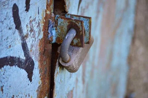 A rusty lock is on a blue door with graffiti on it Foto stock