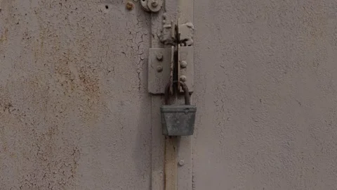 A Rusty Lock on a Metal Door Featuring Weathered Paint and Visible Signs of Age Stock Footage 309814562