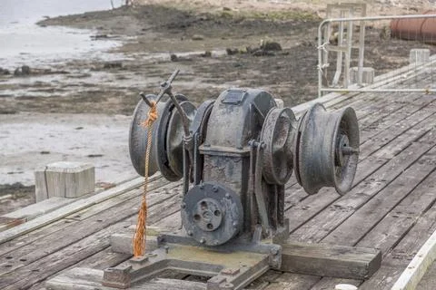 Rusty maritime winch rests on weathered wooden deck Stock Photos