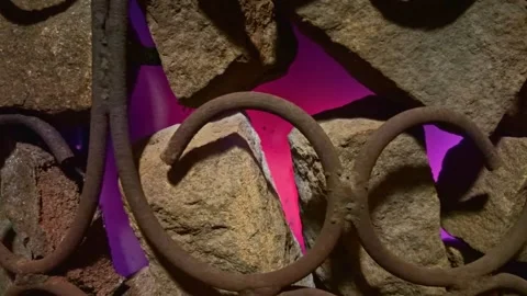 Rusty metal bars intertwining with natural rocks, glowing magenta light in Stock Footage 327892873