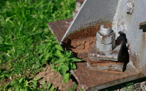 On the rusty metal base of the column, a rusty bolt is firmly attached Stock Photos