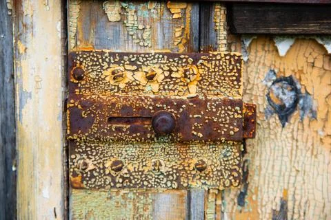 Rusty metal bolt, latch close-up on old shabby wooden door. Chunks of paint Fotos de archivo