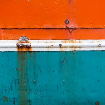 Rusty metal bow of old ship hull in orange blue and white Foto stock