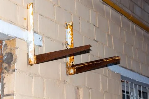 Rusty metal brackets mounted on a white brick wall of an old industrial 스톡 사진