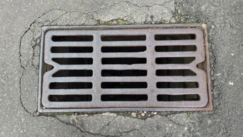 Rusty metal drain grate with horizontal slats in cracked asphalt Stock-Footage 344041451