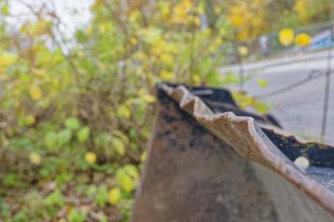 Rusty metal edge of an old object with blurred autumn foliage background Stock Photos