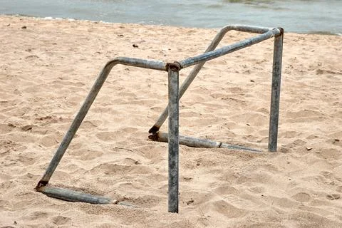 Rusty Metal Frame on Sandy Beach Near Calm Water During a Cloudy Day Stock Photos