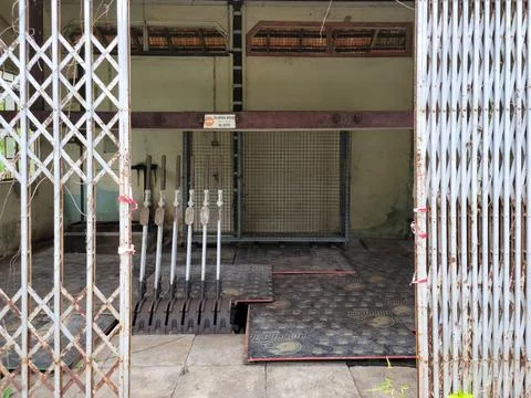 Rusty metal gates frame a dilapidated, empty doorway Stock Photos