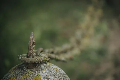 Rusty metal hook attached to a weathered stone with moss, chain extending i.. 스톡 사진