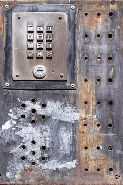 Rusty metal intercom keypad on industrial wall Stockfoto's