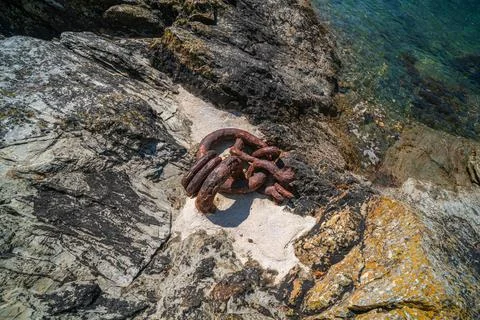 Rusty metal mooring rings embedded in rock on a sunny summer day Stock Photos